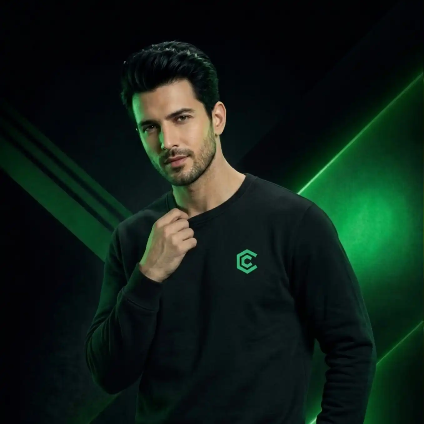 Man wearing a black sweatshirt with a green logo against a dark background