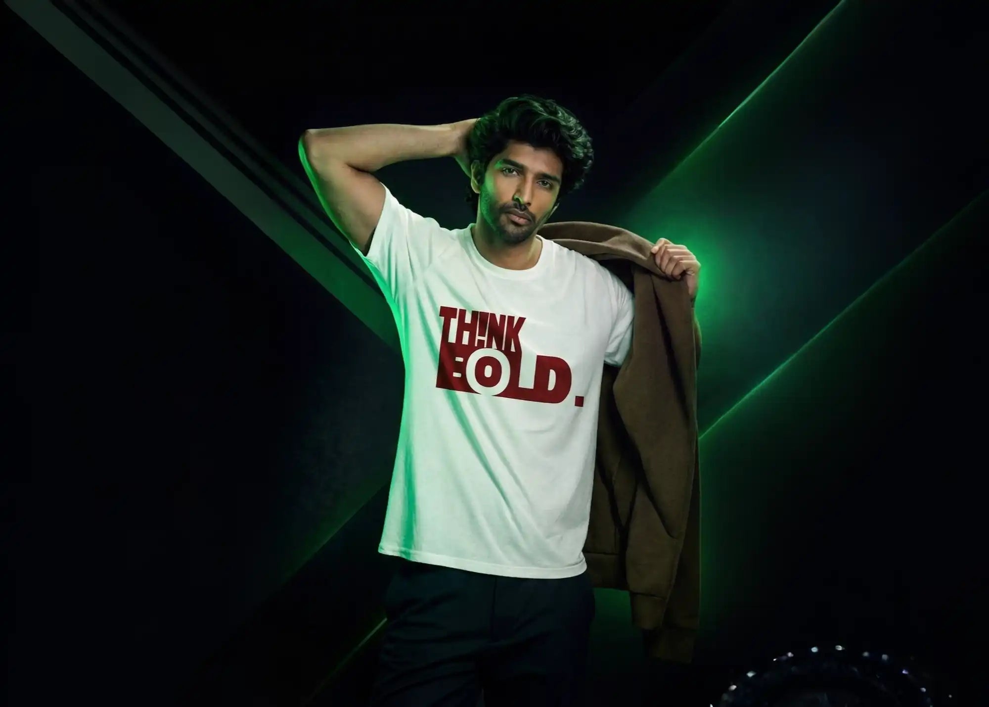 Man wearing a white t-shirt with 'THINK FOLD' text, holding a brown jacket against a dark background.